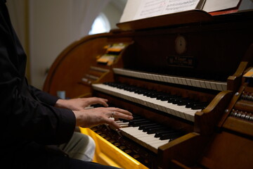 hands playing a musical instrument organ, keys. A close-up man playing a church organ, his hands gracefully gliding over the keys and registers