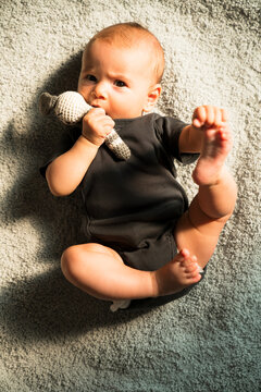 Newborn baby lying on soft carpet, holding crochet bunny in her 