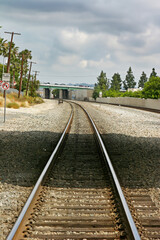 Fototapeta premium Railroad tracks running into the distance and under an overpass on stormy cloud filled day.