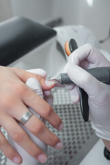 Hardware Manicure process in a beauty salon close up. Professional manicurist in gloves cut the cuticle with a electric file. Concept nails and hands care 