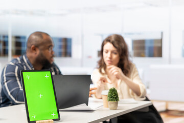 Businessman meets with woman realtor regarding an office tour, discussing at desk next to chroma key mockup. Contractor presenting high class office space blueprints for renting.