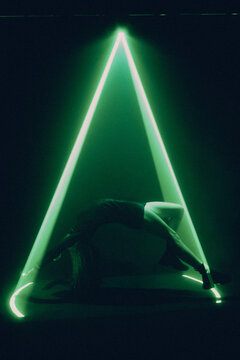 portrait of young woman levitating inside a beam of bright green light