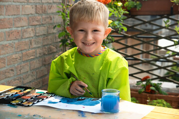 Portrait Of a Cute Caucasian boy painting with paints