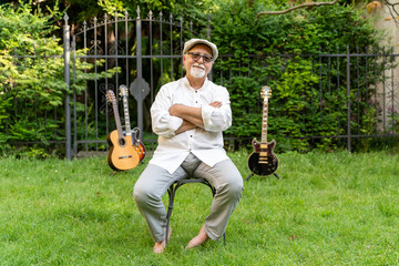 middle-aged professional guitarist posing sitting in his home garden surrounded by his guitars
