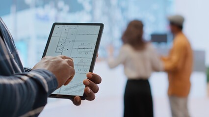 Financier realtor and client examining blueprints on a tablet and establishing the renovation plans before reaching an agreement. Businessman planning an investment during office tour. Camera B.