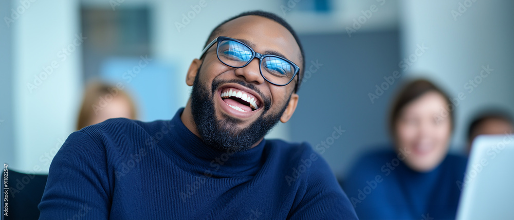 Wall mural A cheerful businessman in a navy blue sweater and glasses laughs joyfully in an office setting. His expression radiates positivity and happiness, capturing a candid moment of workplace camaraderie.