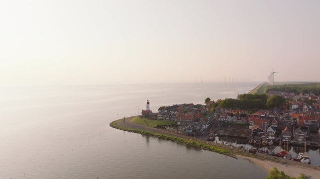 Aerial view of Urk's iconic lighthouse and coastal town at sunrise, showcasing the scenic waterfront and tranquil morning atmosphere of a Dutch town