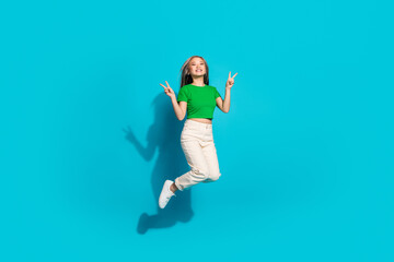 Full size photo of nice young girl jump show v-sign empty space wear t-shirt isolated on teal color background