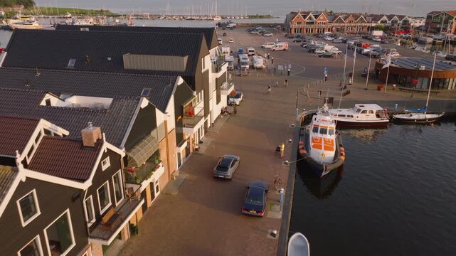 Aerial view of the charming waterfront town of urk, featuring picturesque buildings, docked boats, and a bustling harbor area during the day