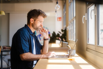 Male Entrepreneur Working On Laptop In Modern Workplace