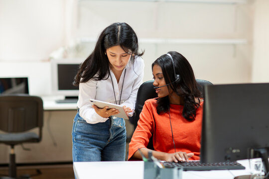 Call center supervisor talking with agent at desk in office