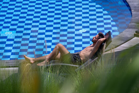 Man lying on pool lounge chair and sunbathing