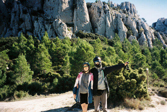 Young couple in helmets hugs opposite the mountains
