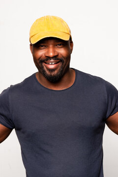 Man smiling with yellow cap, wearing navy blue t-shirt 