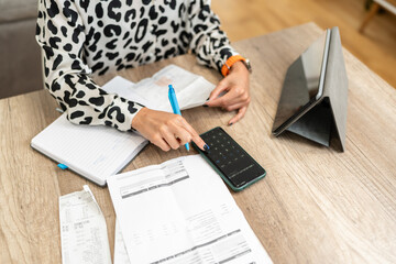 Accountant calculating monthly expenses with calculator and smartphone