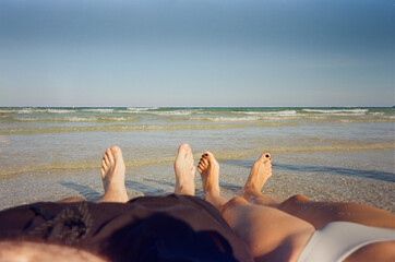 Unrecognizable couple lying on sandy beach