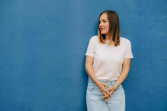 Woman in casual clothing standing against blue wall