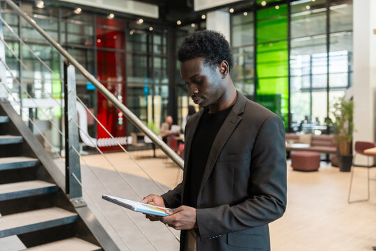 Focused Black Man Reading Reports In The Office
