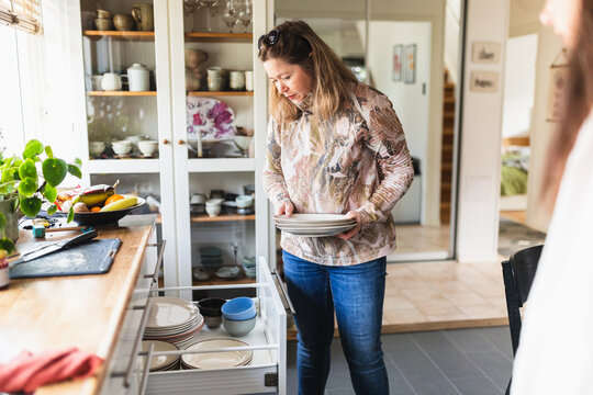 Woman Taking Out Plates in Kitchen