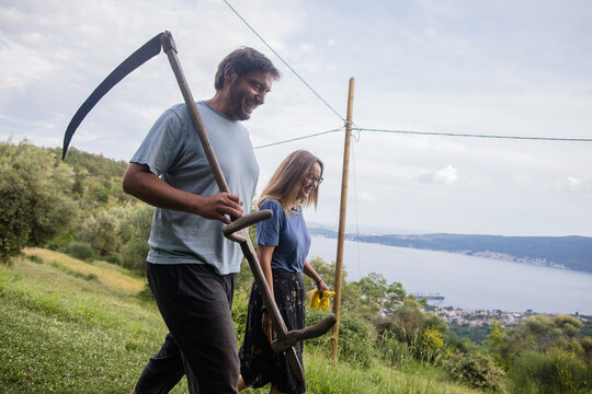 Cheerful spouses with a scythe are going to haymaking