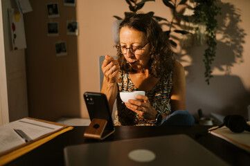 middle aged office worker at home eating lunch at desk