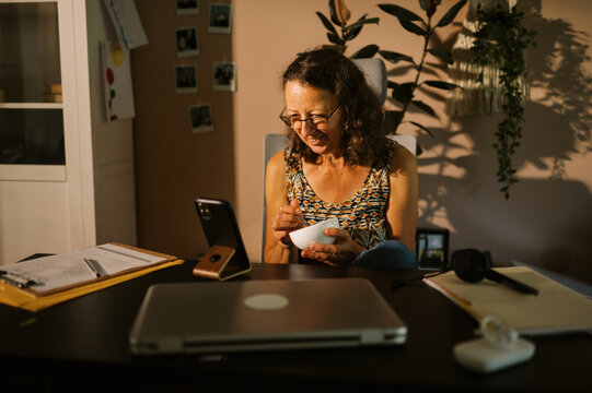 middle aged office worker at home eating lunch at desk