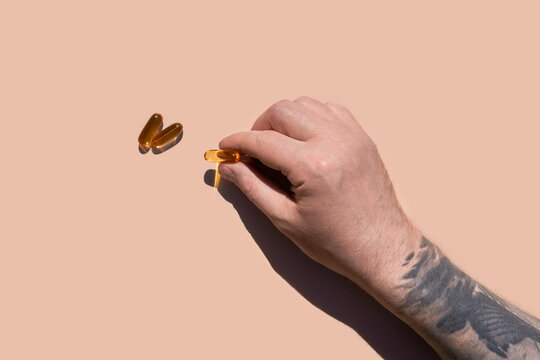 Male hand holding pills in sunlight. Studio shot with copy space