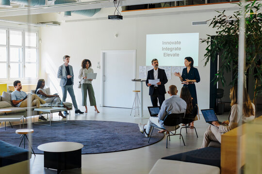 Diverse team listening to business people giving a presentation