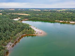 Fototapeta premium Aerial drone view of Bawsey old gravel pits lake. Green water, trees, sand and fields landscape. Bawsey Country Park, King's Lynn, Norfolk, England, UK