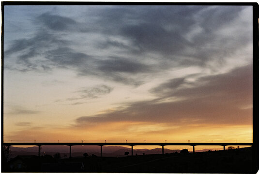 Silhouette of a Bridge at Sunset Over Rolling Hills