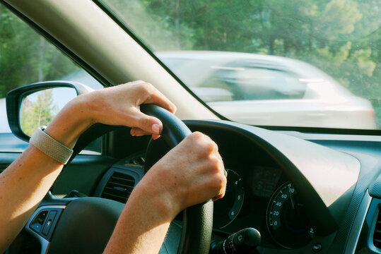 The woman's hands firmly grasp the steering wheel of the car
