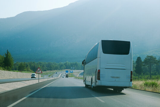 A white tourist bus drives on highway