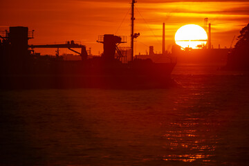 Obraz premium 関門海峡の日没と横切ろうと進む船影20240720-2