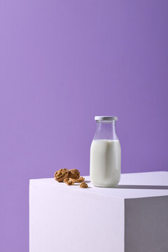 Glass of fresh milk with nuts on white table