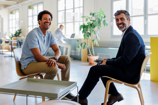 Two businessmen smiling during a meeting in a modern office