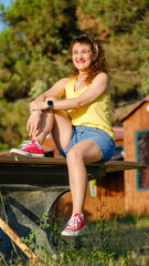 A beautiful middle-aged woman models stylishly in a forested area on a summer day, posing stylishly in her colorful summer outfit