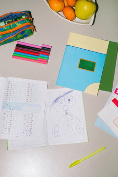 Kid's drawing in a notebook next to the textbooks and workbooks 
