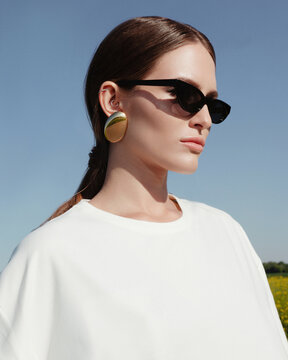 The portrait of a girl with black sunglasses and golden round earrings