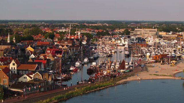 Allure of a dutch harbor in urk, Holland, with vibrant boats and buildings lining the bustling waterfront. Picturesque scene capturing coastal life in Europe