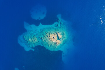 Aerial view of a small rocky island surrounded by deep blue water.