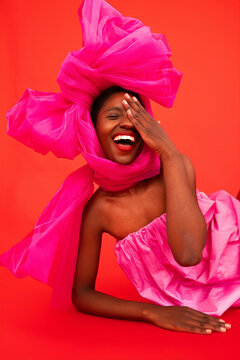 Happy black model in pink bow touching face