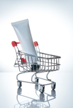 White blank cream tube in a shopping cart. Modern still life