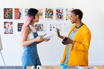 Two designers discussing creative projects in a modern office.