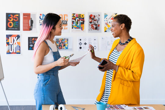 Two designers discussing creative projects in a modern office.