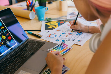 Graphic designer at work with a laptop, color swatches, and sketches