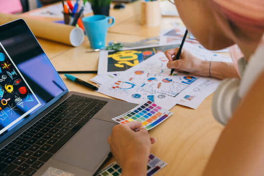 Graphic designer at work with a laptop, color swatches, and sketches