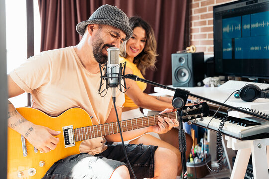 Performers playing piano and singing while recording in studio
