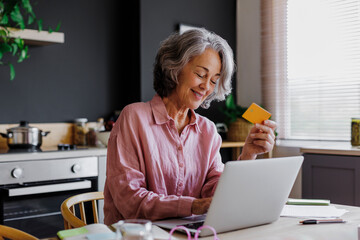 Woman using laptop and credit card for online shopping at home
