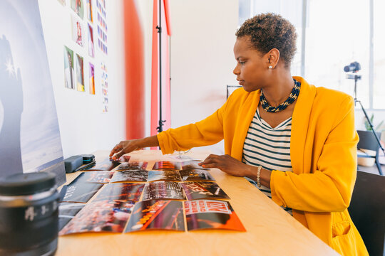Creative professional arranging photographs on desk in bright office
