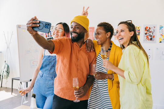Colleagues celebrating and taking a group selfie during office party.